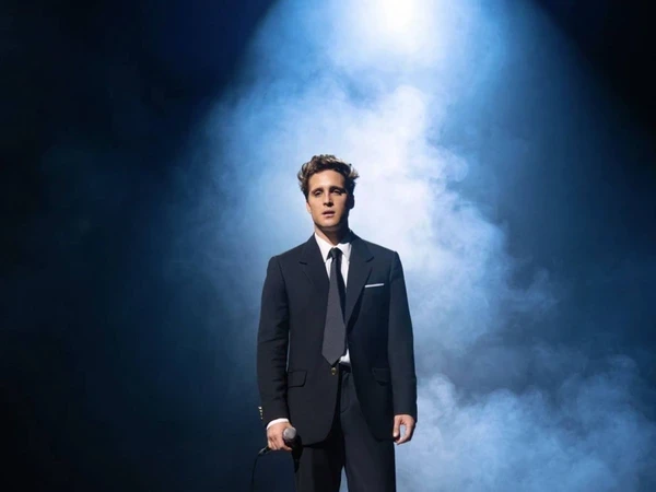 Luis Miguel stands on stage with spotlight in "Luis Miguel: The Series".